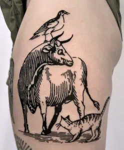 Bold black ink tattoo of a goat, bird, and cat design