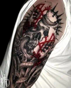 Skull and dagger tattoo with red occult symbols on upper arm, in black and grey realism style